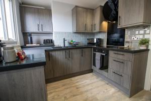 kuchnia z drewnianymi szafkami i czarnymi blatami w obiekcie Modern and Stylish Apartment- Short Walk to Beach w mieście Paignton
