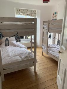 two bunk beds in a room with wooden floors at Hobbes Cottage, pets allowed in Tenby