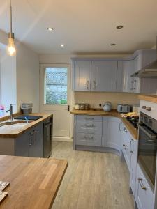 a kitchen with gray cabinets and a wooden floor at Hobbes Cottage, pets allowed in Tenby