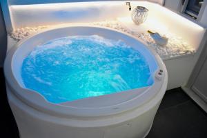 a bath tub with a blue water in it at Ariana Eco Suites Adults Only in Fira +28 photos