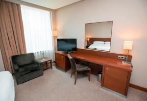 a hotel room with a couch, chair, desk and a television at FLY INN BAKU in Baku