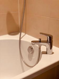 - Baño con lavabo y bañera con grifo en De Parys Guest House - Fully Airconditioned en Bedford