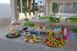 a table with plates of fruit on it with tables and chairs at B&B Poseidon in Punta Prosciutto