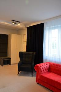 een woonkamer met een rode bank en een stoel bij Zamkowe Apartamenty in Sandomierz