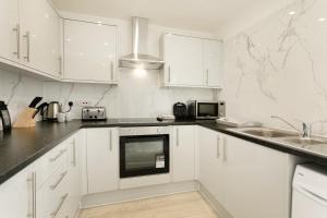 諾丁漢的住宿－Nottingham Serviced Accommodations，白色的厨房配有白色橱柜和水槽