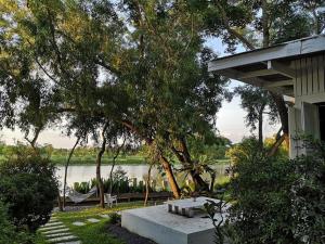 a picnic table in front of a house next to a lake at Arthit -Tara Lodge in Prachin Buri