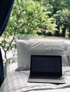 a laptop computer sitting on a bed with a pillow at Arthit -Tara Lodge in Prachin Buri