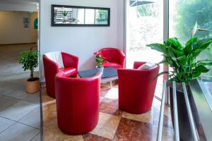 オーバーニュにあるLogis Noemys pont de l'Etoile - ex Mas de L'Etoileの赤い椅子とテーブルと植物のある部屋