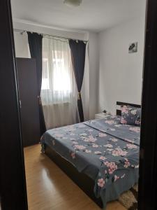 een slaapkamer met een bed met een blauwe deken met bloemen bij Apartament Maria in Floreşti