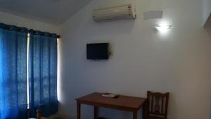 a room with a tv and a table and a window at Nalla Eco Beach Resort in Pondicherry