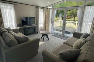 a living room with a couch and a television and a table at Elegant Lodge with Hot Tub in Barmby on the Moor
