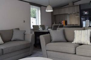 a living room with two couches and a kitchen at Elegant Lodge with Hot Tub in Barmby on the Moor