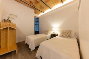 two beds in a room with white walls and a window at Bravissimo Cort Reial Entresol B in Girona