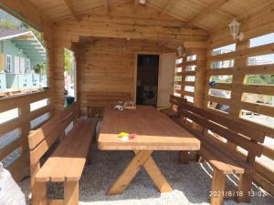 a wooden cabin with a wooden table and benches at Lazurny in Gagra