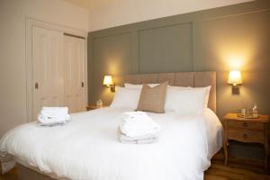 a bedroom with a large white bed with towels on it at Patsy’s Corner Cottage in Enniskillen