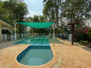 a swimming pool with a green canopy over it at Saiyok River House in Sai Yok