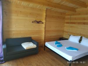two beds and a couch in a room with wooden walls at Lazurny in Gagra