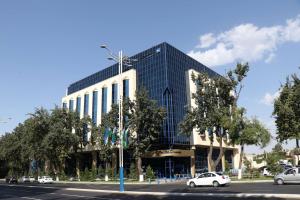 um grande edifício de vidro com carros estacionados numa rua em Radisson Blu Hotel, Tashkent em Tashkent
