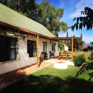 a house with a green roof and a patio at Pepper Tree Cottage in De Rust