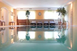 einen Pool mit Stühlen und Tischen in einem Zimmer in der Unterkunft Hotel Allgäuer Hof in Oberstaufen