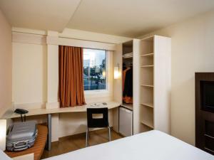 a room with a bed and a desk and a window at Ibis Joao Pessoa Praia in João Pessoa