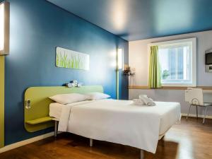 a bedroom with two beds and a blue wall at ibis budget Belo Horizonte Afonso Pena in Belo Horizonte