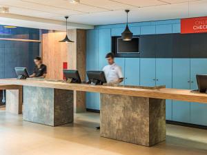 two people standing at a reception desk with laptops at ibis Santos Valongo in Santos