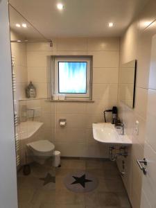 een badkamer met een wastafel, een toilet en een raam bij Haus Cornelia in Einruhr