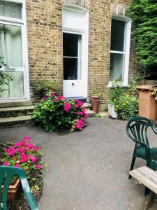 un patio con 2 sillas y flores frente a un edificio en Amhurst Hotel en Londres