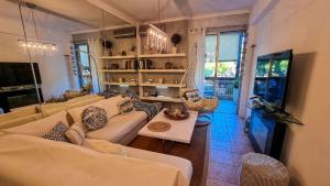ein Wohnzimmer mit weißen Sofas und einem TV in der Unterkunft South Coast Voula Beach Sea RIVIERA Suite in Athen