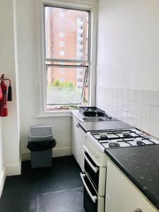 a small kitchen with a stove and a window at Amhurst Hotel in London