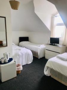 a bedroom with two beds and a mirror at Amhurst Hotel in London