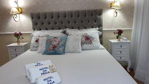 um quarto com uma cama grande com lençóis brancos e almofadas em Hotel da Praia em Vila Velha