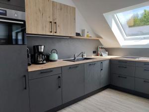 a kitchen with gray cabinets and a sink and a window at Elpe Apartments Hochsauerland in Elpe