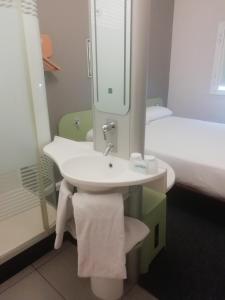 SUN1 MIDRAND في ميدراند: حمام مع حوض ومرآة وسرير