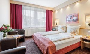 ein Hotelzimmer mit einem großen Bett und einem Schreibtisch in der Unterkunft Schlossberghotel Oberhof in Oberhof