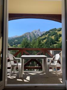 d'une table et de chaises blanches sur un balcon avec vue sur les montagnes. dans l'établissement Studio chaleureux et ensoleillé !, à Allos