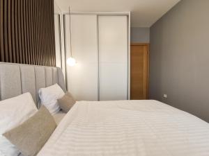 sypialnia z dużym białym łóżkiem z białą pościelą w obiekcie Design Apartment at CITY QUART w mieście Podgorica