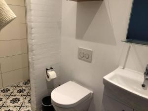 a white bathroom with a toilet and a sink at Tøndegården 2 rooms apartment in Odense +4 photos