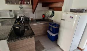 W kuchni znajduje się biała lodówka i kuchenka mikrofalowa. w obiekcie Flat no bosque da praia Pipa-RN w mieście Pipa