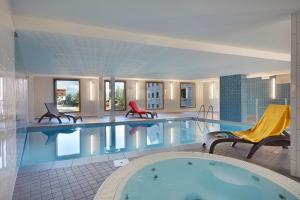 a large pool in a hotel with two chairs at Résidence Néméa Le Hameau - Les Deux Alpes in Les Deux Alpes