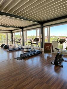 een fitnessruimte met loopbanden en crosstrainers in een kamer met ramen bij City Hotel Fortuna Reutlingen in Reutlingen