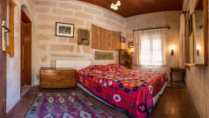 a bedroom with a bed with a red comforter at Kirkit Hotel in Avanos
