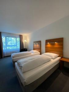 ein Hotelzimmer mit 3 Betten und einem Fenster in der Unterkunft City Hotel Fortuna Reutlingen in Reutlingen