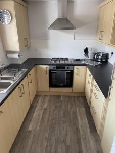 a kitchen with wooden cabinets and a stove top oven at Burry Port Harbour Apartment in Burry Port