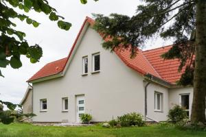 a white house with an orange roof at Ferien unnern Appelboom (80m2 Wohnung mit großem Garten) in Groß Kordshagen