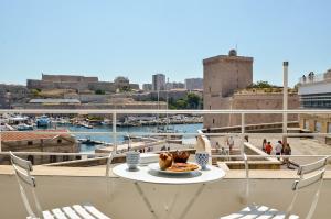 a table on a balcony with a view of a harbor at MASSILIA BLUE - Grand appartement refait à neuf avec vue sur le Vieux Port in Marseille