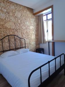 a bedroom with a white bed with a brick wall at QuimPecável in Figueira da Foz