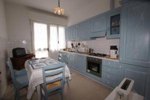 a kitchen with blue cabinets and a table and chairs at Casa Belvedere (CITRA 008026-LT-0015) in Diano Castello