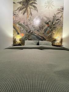 een slaapkamer met een groot bed met tropisch behang bij Patenier Hidden Garden 1bdr with garden in Luik